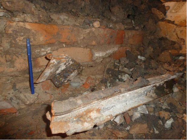 Partes de un riel ferroviario y fierros retorcidos impregnados los perfiles de suelo de ladrillo