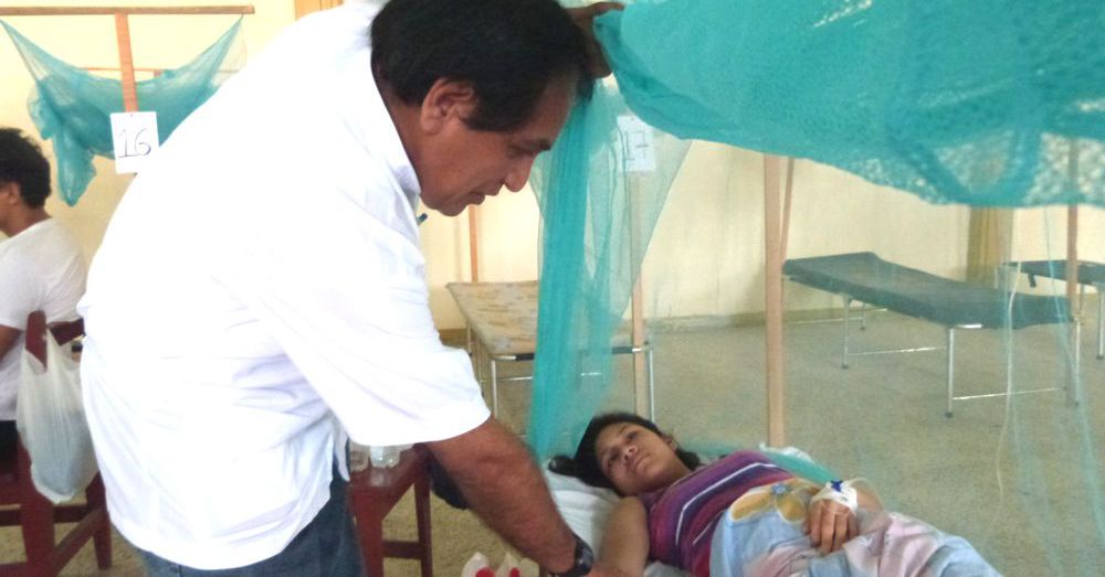 Infectólogo del Hospital Apoyo Iquitos, Dr. Moisés Sihuincha Maldonado, observando a una paciente.